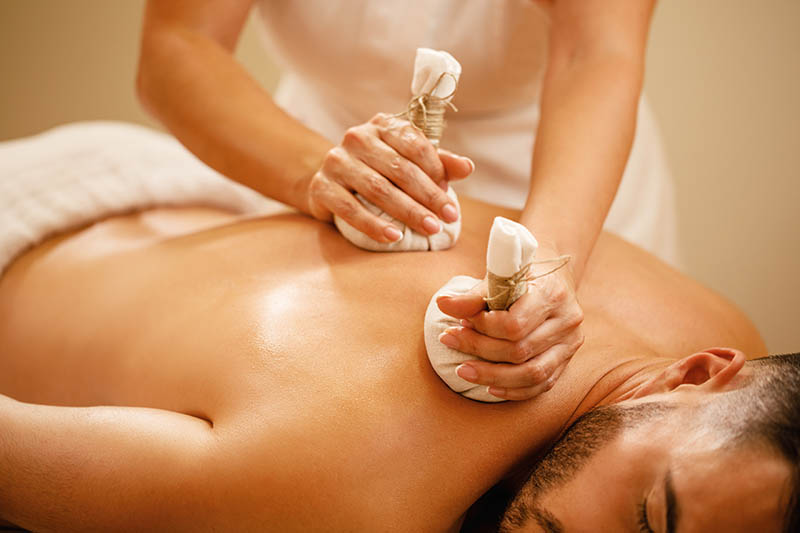 A handsome young man receiving a sand bag massage
